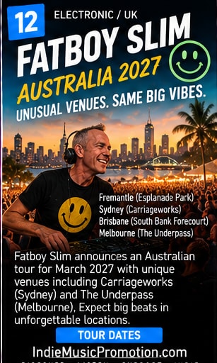 Fatboy Slim wearing yellow smiley t-shirt smiling at DJ decks outdoors.