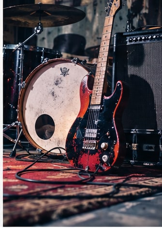 Distressed electric guitar and amplifier on oriental rug in rehearsal space for Public Figures.